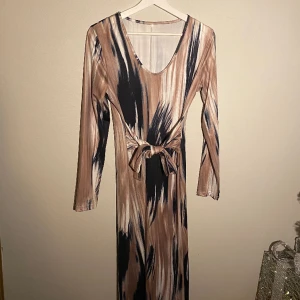 Mönstrad klänning med knytning i midjan  - Lång klänning med knytning i midjan, mönster som gör en illusion av smalare midja. Nypris 259 Aldrig använd endast testad. Storlek L