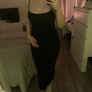 Klänning - Svart lång tajt klänning med ett kors i ryggen, ganska så stretchig,knappt använd💕lite genomskinlig 