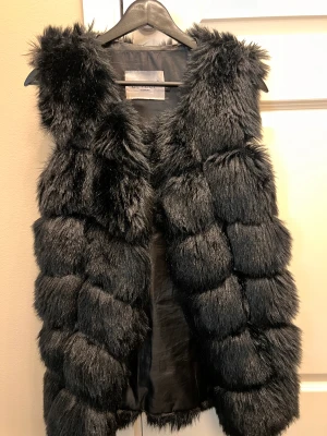 Pälsimitation väst från Lovely of Sweden - Väst i pälsimitation från Lovely of Sweden som är använd vid fåtal tillfällen. Hel och fin. Går att knäppa (spänne fram)  Nypris: 799:-