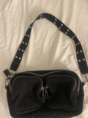 Svart handväska med silvriga detaljer - Svart handväska som kommer ifrån Gina tricot. Köptes för ca 400/300kr. Använd men inte synbart endast lite på bandet. Har endast det korta bandet kvar.  Fin men tappat intresset för den. Två stora fack och tre lite mindre fack. Kontakta för fler bilder!