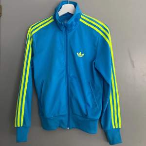 En turkos och grön adidas kofta kommer inte till användning men är använd