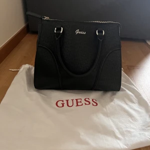 Guessväska - Säljer min Guessväska, oanvänd. Köpt i Australien. Dustbag och kvitto medföljer. 