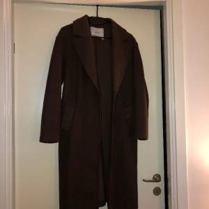 Knälång mörkbrun kappa i storlek XS. Köpt för ett år sen, sparsamt använd.