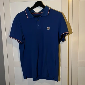 Blå monlcer piké - Blå moncler piké i bra skick. Den är sparsamt använd och har Inga defekter. 8/10. Köpt här på plick för 1050kr. Den är large men sitter som M. Skriv för fler frågor eller fler bilder.