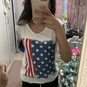T shirt med usa flaggan på - En t shirt med en usa flagga på med meningar inuti tröjan så de syns på baksidan, i storlek M men passar mig som har XS