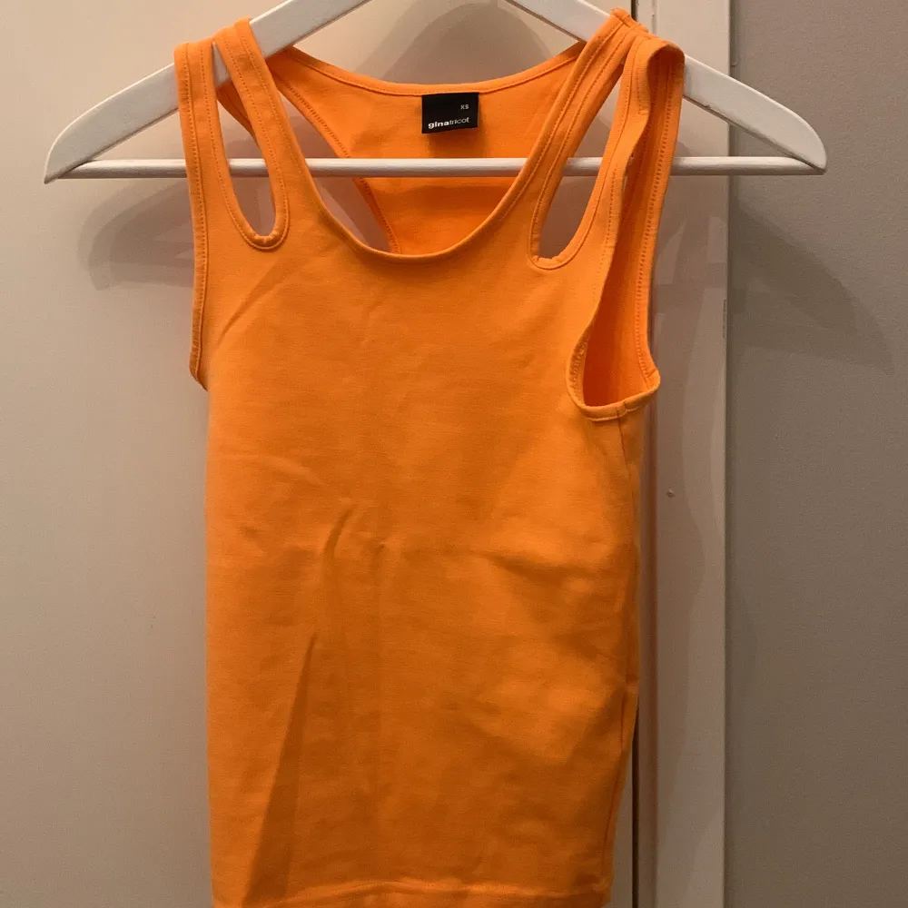 Ett orange linne som sitter lite tajt Aldrig använd. Toppar.
