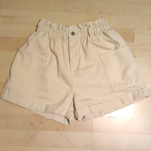 Beige shorts med stora fickor - Sparsamt använda men i mycket fint skick shorts med många stora fickor.  De är mjuka och lätta och smala i siluetten.  I setet ingår ett bälte med spänne.