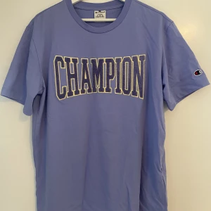 Champion T-shirt  - T-shirt från champion i en pastellila färg med broderad text med fyllning. Enbart använd 2/3 tillfällen!