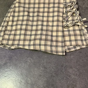 Beige rutig shortskjol - Detta är ett par shorts som ser ut som en kjol. Väldigt fin men har dock aldrig använt den själv för märkte de inte riktigt va min stil men den e jättebra skick eftersom den då aldrig e använd