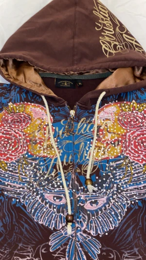 Ed Hardy hoodie - Snygg ed hardy hoodie! Sitter tight/skräddarsytt mot kroppen. Tröjan är i bra skick, inga visuella defekter.  Passar dig som är mellan 157-163 Står att tröjan är XL (barnstorlek) men den sitter som XS.