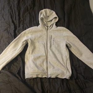 Grå Sail racing zip up - Säljer denna snygga zip up tröjan eftersom den inte passar mig. Den är i nyskick och använd fåtal gånger. Nypris: 1300kr. Pris kan diskuteras.