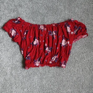 Röd topp - En supersöt röd topp som är croppad med ett fint blommönster. I storlek L (är liten i storleken) från divided. 