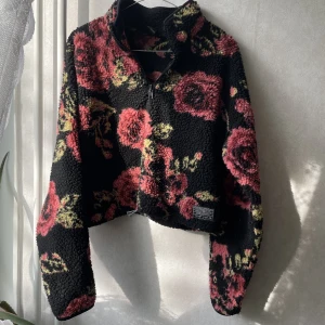 UO Rosmönstrad crop teddy  - Svart cropped teddy i rosmönster från Urban Outfitters 