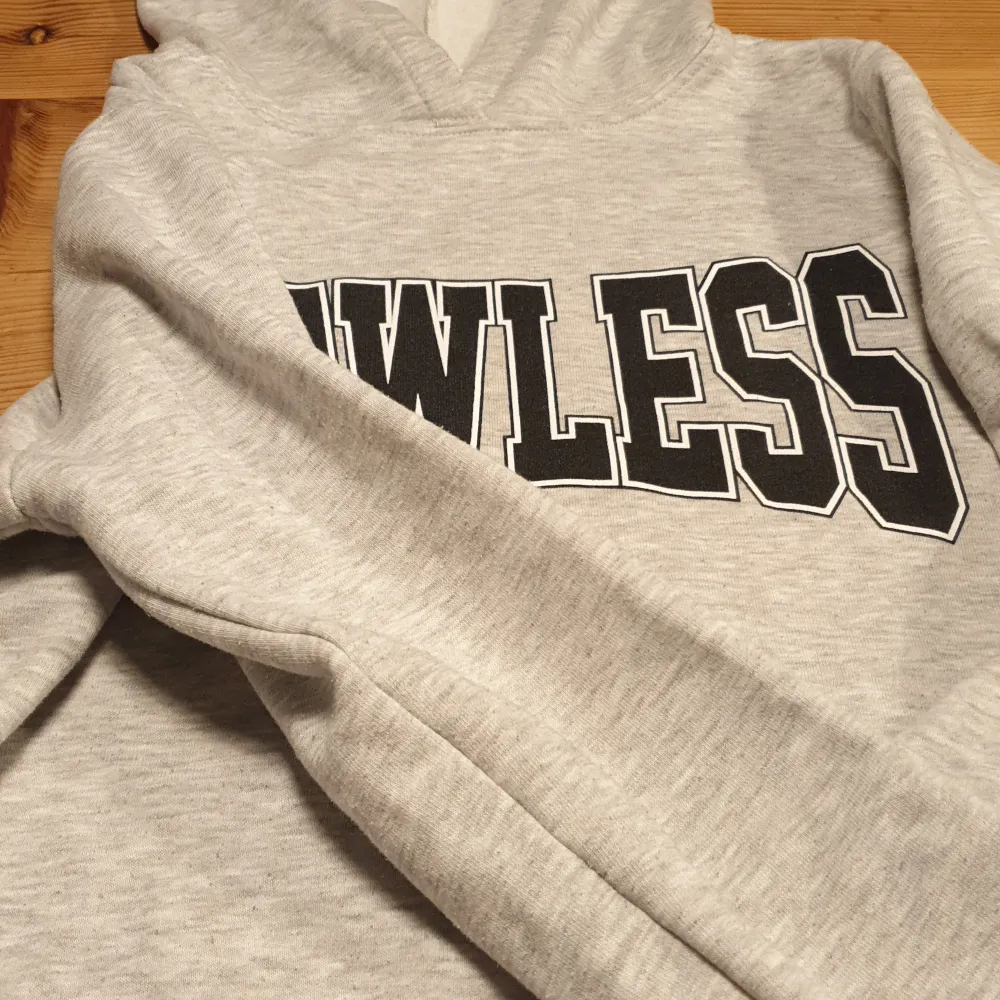 En grå hoodie med luva och text 