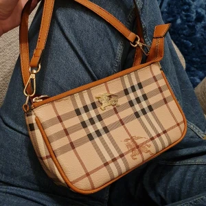 Liten väska - Söt liten väska. Dragkedjefästet saknas och är ersatt av en nyckelring. Bandet till är ganska långt. Köpt secondhand. Troligtvis inte äkta