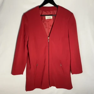 Kavaj - Röd kavaj i mjukt och fint material. Bilderna gör den inte rättvisa, den är väldigt smickrande på. Går ner över rumpan och är fyrkantig i formen.  Längd: 80cm Ärm: 56cm   Skicka DM vid frågor. ☆．。･