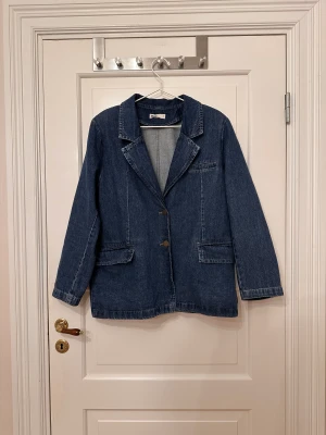 Jeanskavaj - Mörkblå jeanskavaj från Gina Tricot i storlek M. Två knappar och fickor. Axelvaddar. Oversized. Använd ett fåtal gånger.