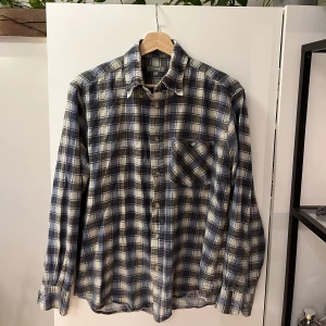 Rutig skjorta  - Blå och vitrutig skjorta med röda detaljer i storlek 39/40. Köpt secondhand men den är i fint skick. Funkar unisex. 