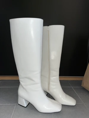 Vita höga boots - Sköna och snygga boots i skinnimitation med mellanhög klack. Bara använda en utekväll. Köpta för 800kr