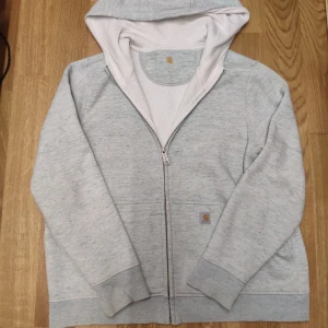 Carhartt Zip Hoodie - Snygg Carhartt Zip. En grå färg med toner av turkos. Mycket bra skick. Står Xl på tröjan men skulle säga mer åt L hållet 