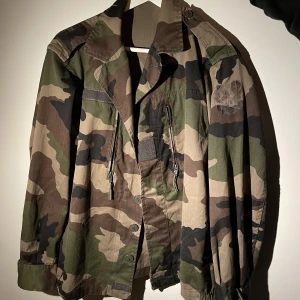Militär jacka  - Militär grön jacka camoflage har ett litet slitage på ena armen som syns på bild annars super fin 