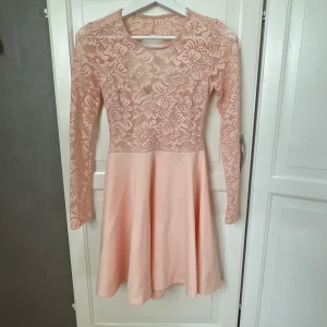 Spetsklänning  - Rosa spetsklänning med långa armar och öppen rygg. Använd 1 gång. Köpt från Nelly. Nypris = 649kr 