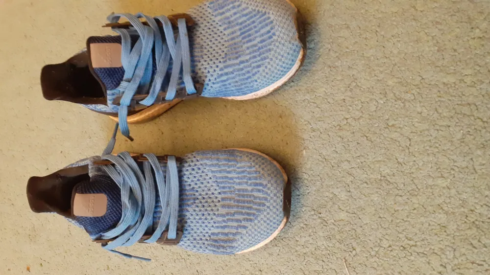 Ett par blåa adidas ultraboost skor som nästan aldrig är använda men undersulan gar gått av och vi har fixat den . Skor.