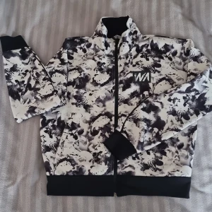 Tränings tröjs - Mönstrad träningströja i svart och vitt. 2 fickor och dragkedja. 146/152