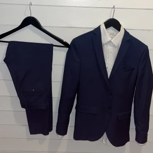 Kostym - 9/10 skick, använd vid 2 tillfällen under 2 års tid. Säljer endast då den blivit för liten. Mörkblå. Allt tillsammans kostade drygt 2500 vid köp.   Bara kostymen - 800  Bara skjortan - 250kr  Allt tillsammans - 950    Skjorta-XS/S  Kavaj-44 Byxor-46