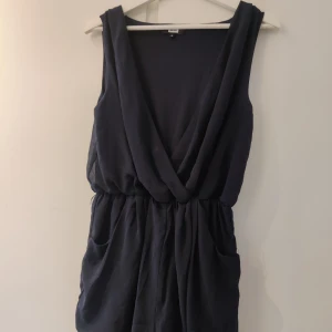 Marinblå jumpsuit Bikbok storlek S - Marinblå jumpsuit från Bikbok, kommer med ett matchande "bälte" som jag glömde ha med på bild. Djupare urringning. Ena öglan för bältet är sönder, se sista bilden. Annars bra skick! Fler bilder kan fås.
