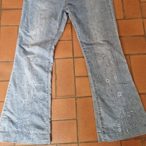 Lågmidjade jeans med blommor och fjäril broderi - Ungefär 90 cm runt midjan Skulle säga är en M/L beroende på hur man vill att den ska sitta. 