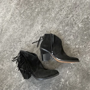 svarta stövletter - svarta stövletter/låga stövlar i mocka med fransar på yttre sidan i lite cowboy-stil. skitsnygga att ha under långa jeans nu till hösten! köpta second hand. 💘💘💓