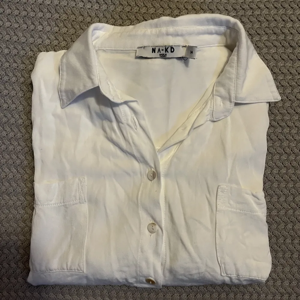 En vit skjorta från na-kd. Tyvärr krympte skjortan i första tvätten vilket gjort att den är för liten för mig. Skulle säga att den är som en storlek 32 snarare än 34, övrigt i fint skick!. Skjortor.