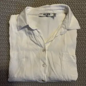En vit skjorta från na-kd. Tyvärr krympte skjortan i första tvätten vilket gjort att den är för liten för mig. Skulle säga att den är som en storlek 32 snarare än 34, övrigt i fint skick!