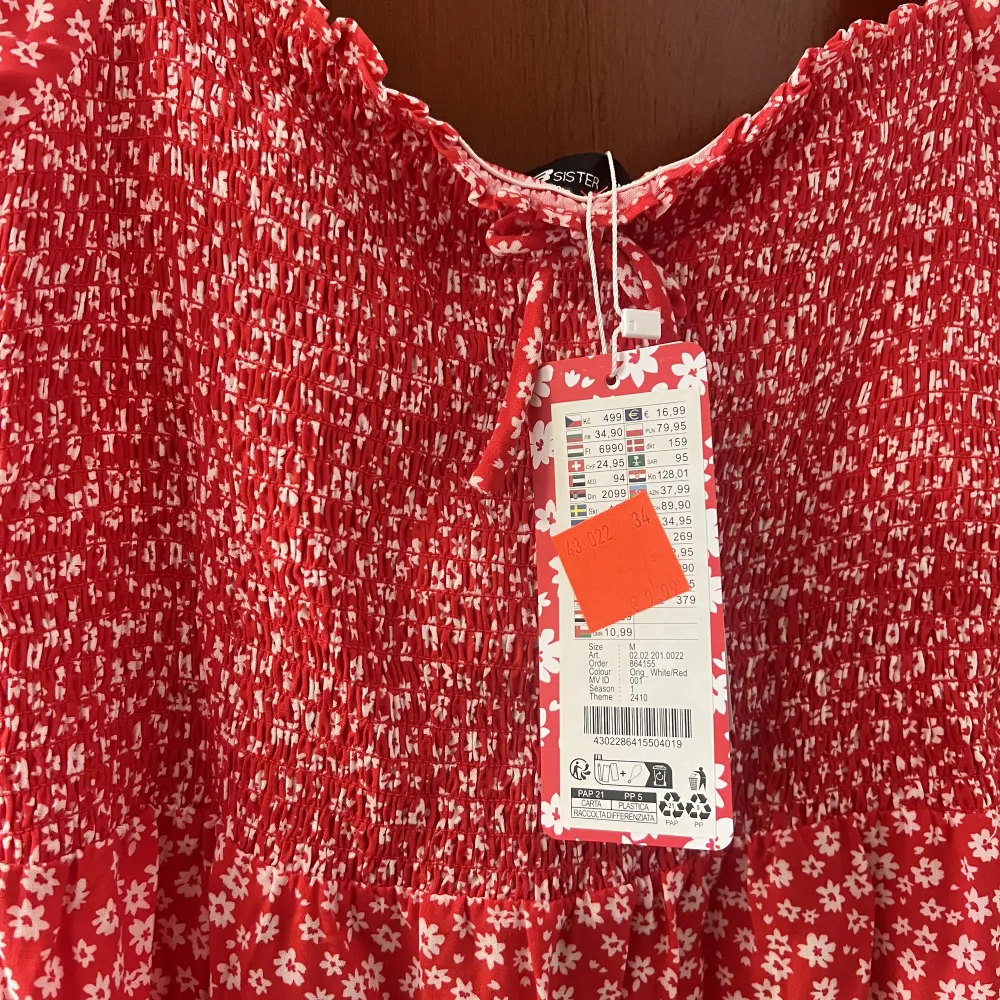 Röd blommig klänning (sundress), aldrig använd med prislapp kvar. Köpt för 10 euro. Klänningar.