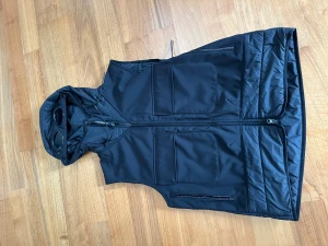 Cp company väst - En svart Cp Company väst i storlek 48 vilket motsvarar medium, . Väster har glasögon på luvan som går att fälla ner med hjälp av knappar. Den är i nyskick eftersom de är bara använd fåtal gånger. Köpt från Nk för 4200. QR KOD OCH KVITTO FINNS.