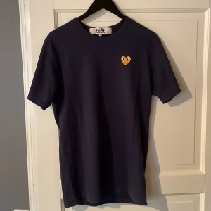 CDG T-shirt  - Mörkblå Comme des Garcon T-Shirt med guldigt hjärta. Minimalt använd i fint skick. 