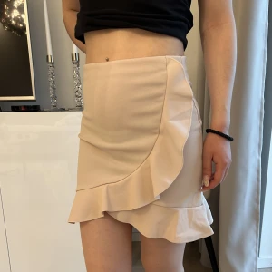 Kjol med volanger  - Beige/rosa kjol från Nelly. Strl XS. Använd en gång, bra skick.