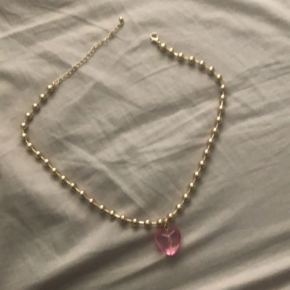 Det här halsbandet är i bra size och har ett rosa hjärta på botten. Accessoarer.