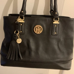 Tommy hilfiger väska - Svart Tommy hilfiger väska i fint sick med många olika fack, finns även ett långt band. Nypris 2000