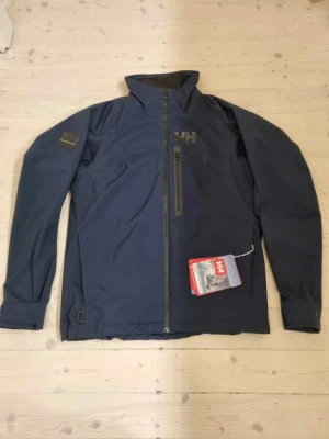 Helly Hansen  - Säljer min splitternya jacka som aldrig är använd! Nypris 1900kr, säljer för 600kr. Klassisk modell för både herr och dam i storlek M.