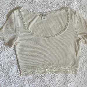 söt topp med spetsdetaljer - En vit crop top från monki med spets. Tyget är ribbat och stretchigt. Skulle säga att storleken är mer av en S än XS. Bra skick förutom två små missfärgningar på ena ärmen (se bild)
