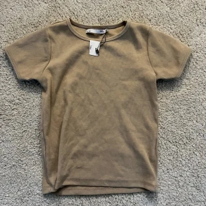 Kortare t-shirt  - En super fin beige topp från lager 157, aldrig använd i storlek 140 så skulle passa dom som har S och M då den är stretchig i materialet🥰