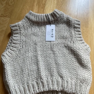 Stickad NA-KD väst - Så snygg croppad beige väst från NAKD. Lappen sitter kvar och den är helt och hållet oanvänd.
