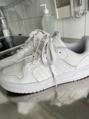 Adidas vita sneakers  - Ett par vita adidas sneakers i strl 40, använda Max 2 gånger och är inte creasade så de ser ut som nya 😊 säljer för jag råkade köpa i en strl för liten så jag använder de aldrig 💗ny pris var runt 700 (köpare står för frakt)
