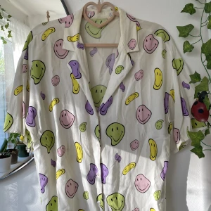Smiley pastel skjorta  - Superfin, lätt, mjuk, vit skjorta från pull&bear. Stl: S, men skulle fungera på XS och M också. Kortärmad med smileys i pastellfärger. Den är i använt skick och har en liten tråd lös (se bild 3), så säljer den billigt. Skriv om du har frågor✨
