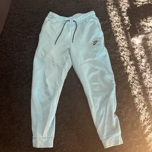 Nike tech byxor - Ljusblå nike tech byxor i stan helt nyskick, har knappt använt de då jag inte gillade dem så mycket. Köpt från nike i gallerian