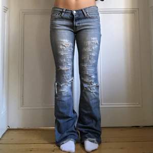 Lågmidjade utsvängda jeans med hål/slitningar på låren, bra skick! Midjemått: 77cm Innerbenslängd: 83cm