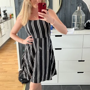 Sommarklänning  - Randig sommarklänning har ett pyttelitet hål i kjolen som knappt syns