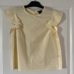 Blus - En ljusgul blus med volanger från Lindex.
